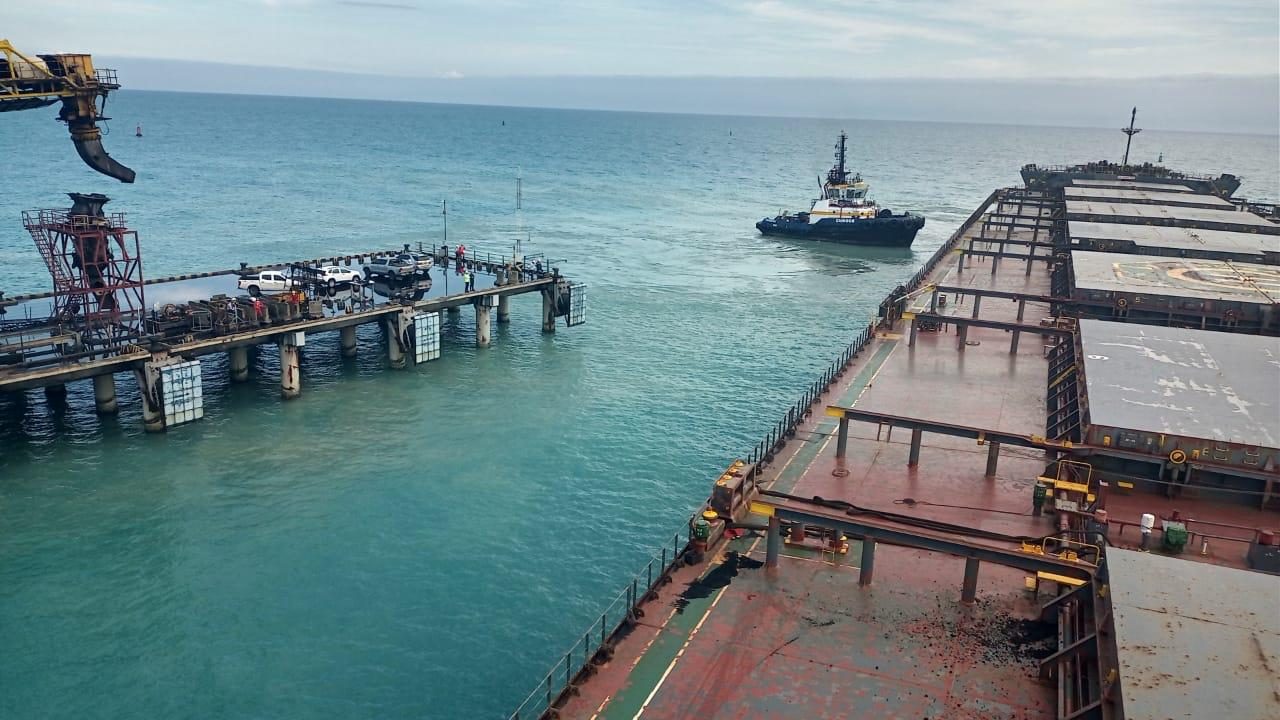 Vista del muelle con buque granelero y remolcador en maniobra